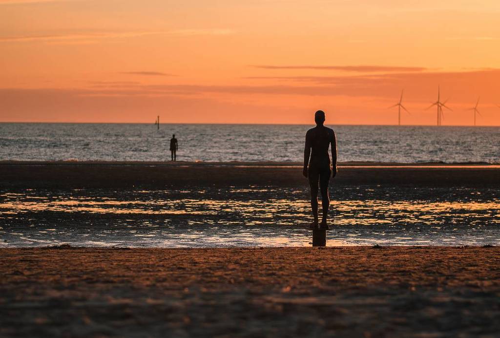 Crosby beach at sunset with Another Place iron men statues